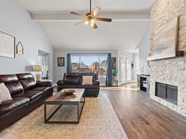 living room featuring ceiling fan, beam ceiling, a stone fireplace, wood finished floors, and high vaulted ceiling