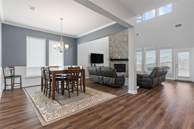 dining area featuring dark wood-style floors, visible vents, ornamental molding, and an inviting chandelier