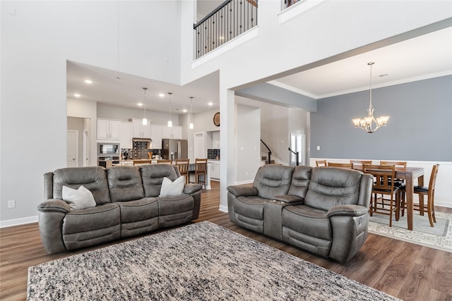 living room with crown molding, baseboards, a notable chandelier, and wood finished floors