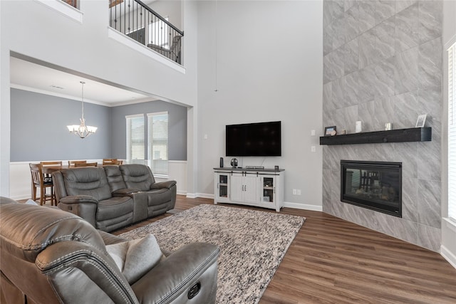 living room featuring a chandelier, a fireplace, wood finished floors, baseboards, and crown molding