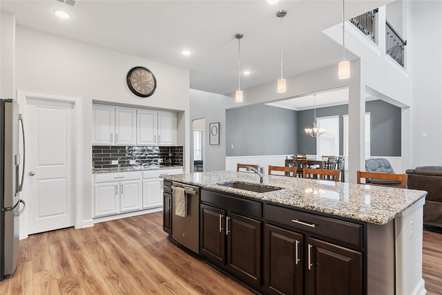 kitchen featuring stainless steel appliances, light wood-style flooring, white cabinetry, a sink, and an island with sink