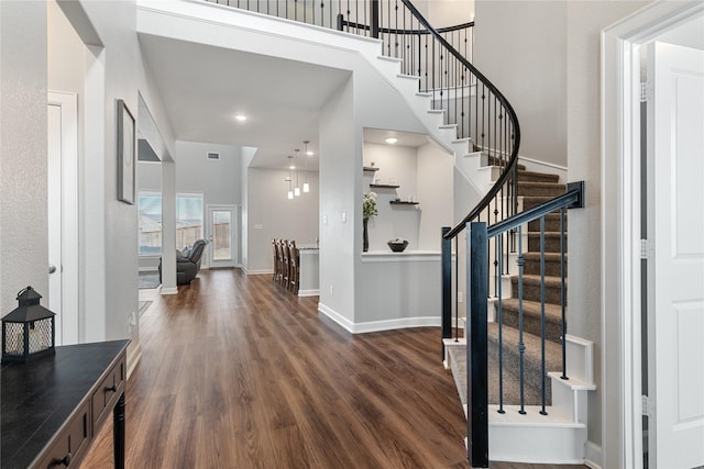 foyer entrance featuring stairway, wood finished floors, a towering ceiling, and baseboards