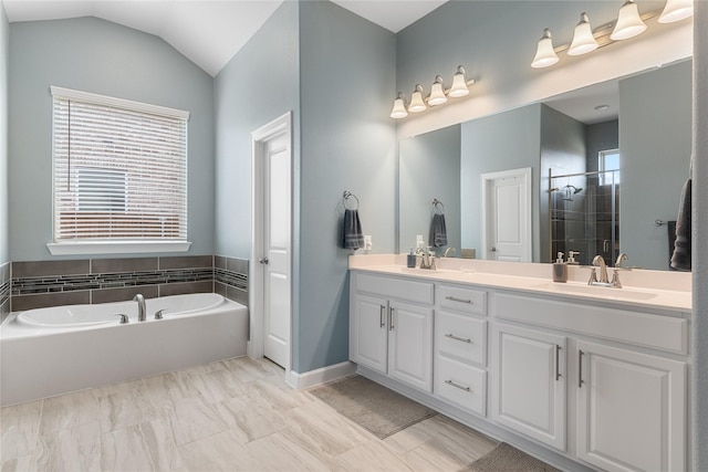 full bathroom featuring a garden tub, double vanity, a stall shower, vaulted ceiling, and a sink