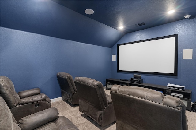 cinema room with lofted ceiling, light carpet, a textured wall, and visible vents