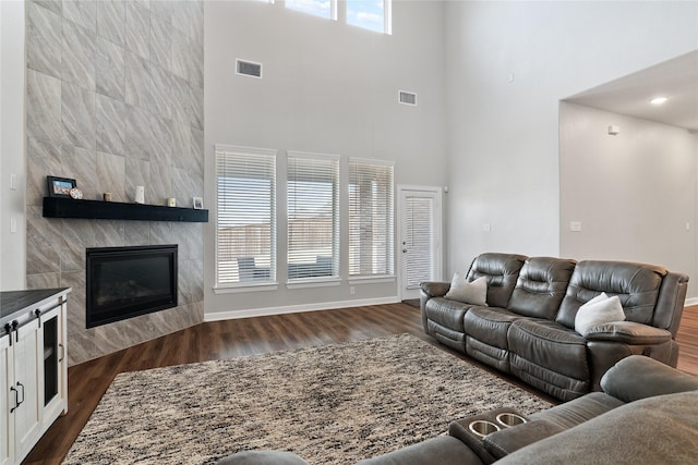 living area with dark wood-style floors, a tiled fireplace, and visible vents