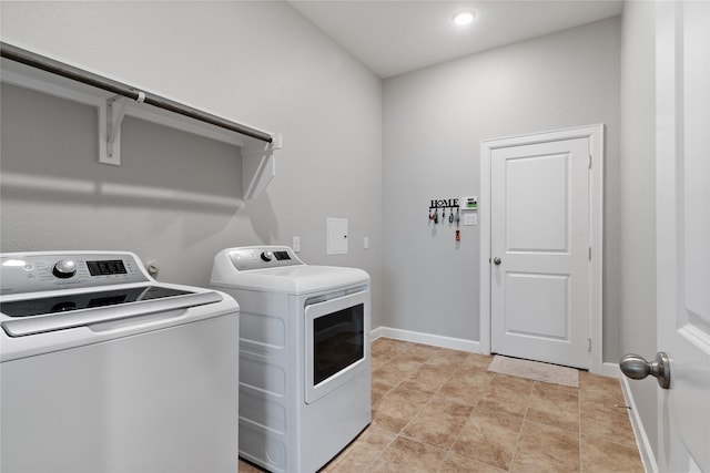 laundry area featuring laundry area, baseboards, washer and clothes dryer, and light tile patterned flooring