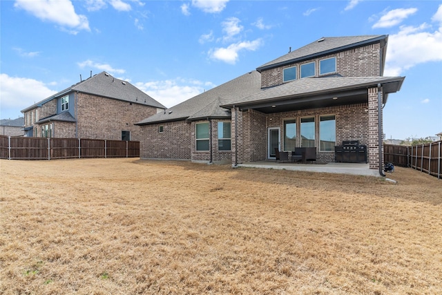 rear view of house with a patio, a fenced backyard, roof with shingles, a yard, and brick siding