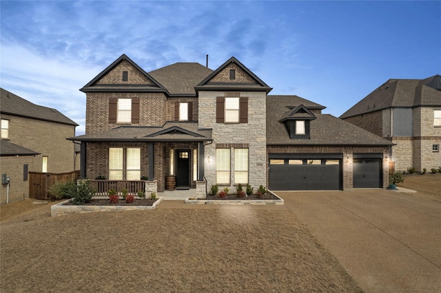 view of front facade with a porch, a garage, concrete driveway, stone siding, and roof with shingles