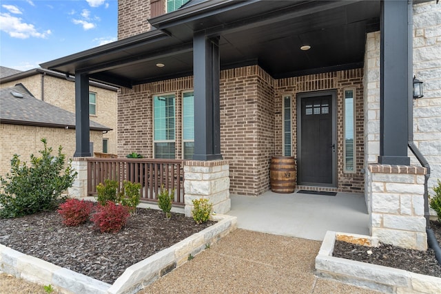 view of exterior entry featuring covered porch and brick siding