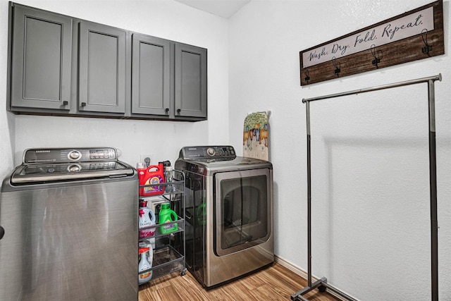 laundry area featuring washer and dryer, cabinet space, and light wood finished floors