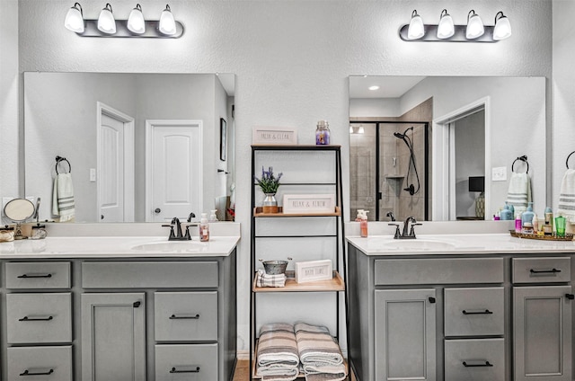 full bath featuring a stall shower, two vanities, and a sink