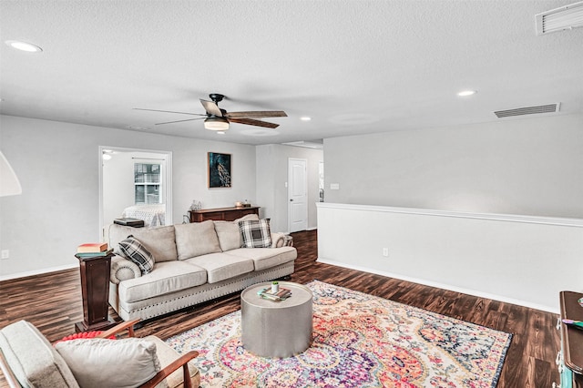 living room featuring a ceiling fan, visible vents, and dark wood-type flooring