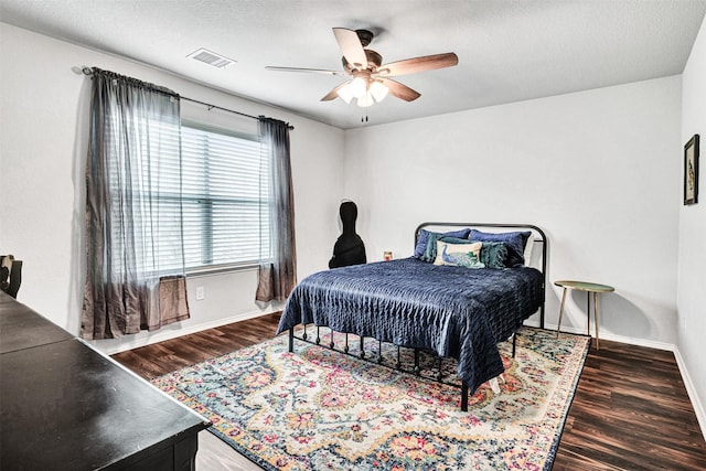 bedroom with a ceiling fan, wood finished floors, visible vents, and baseboards