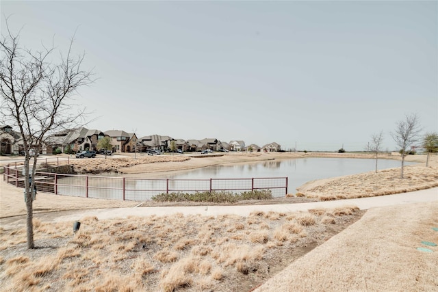 view of yard featuring a water view, fence, and a residential view