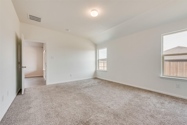 empty room featuring vaulted ceiling, carpet, visible vents, and baseboards