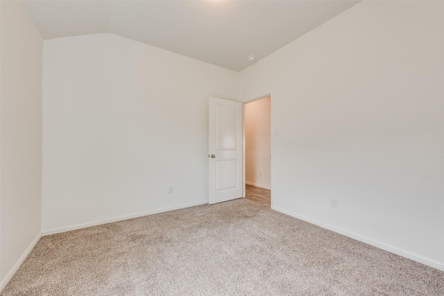 empty room with carpet, lofted ceiling, and baseboards