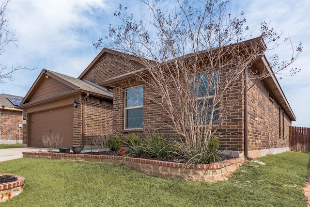 view of front of house featuring brick siding, concrete driveway, fence, a garage, and a front lawn