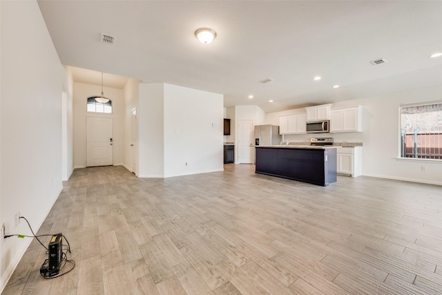 kitchen featuring stainless steel appliances, open floor plan, and light wood-style flooring