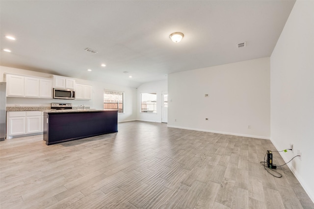 kitchen featuring appliances with stainless steel finishes, open floor plan, white cabinetry, and light wood-style floors