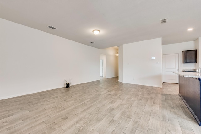 unfurnished living room with visible vents, light wood-style flooring, and baseboards