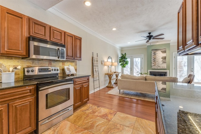 kitchen with appliances with stainless steel finishes, french doors, ornamental molding, and decorative backsplash