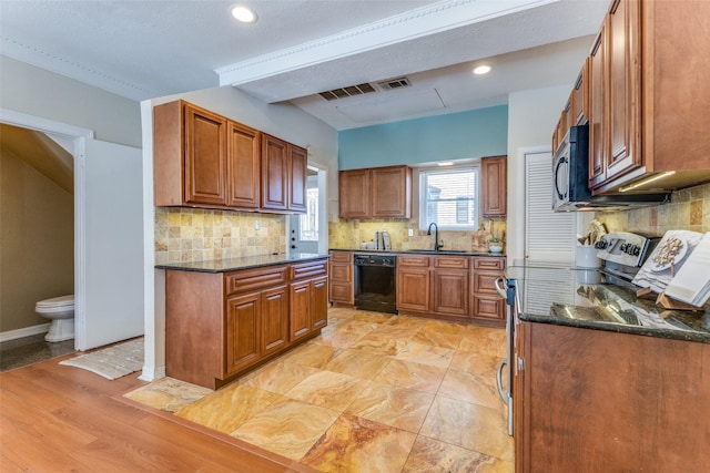 kitchen with brown cabinets, tasteful backsplash, visible vents, a sink, and dishwasher