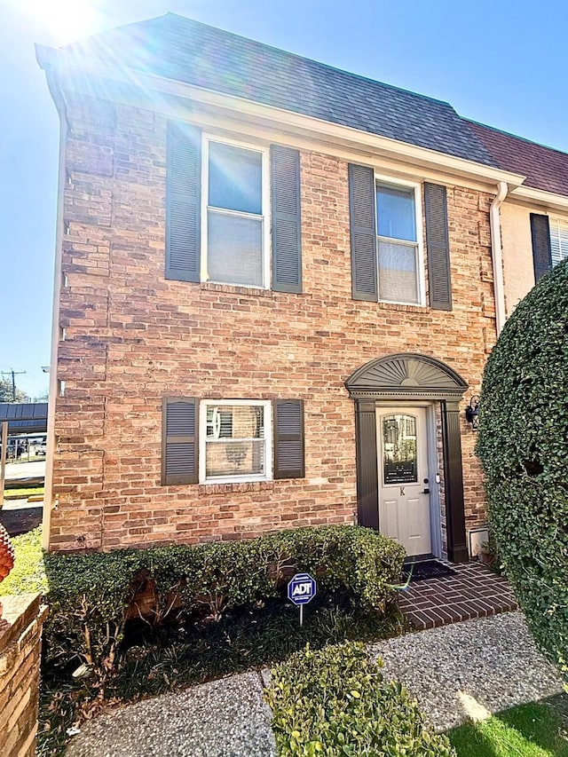 view of front of house with a shingled roof and brick siding