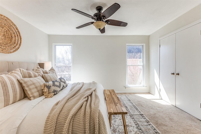 carpeted bedroom featuring multiple windows, a closet, and a ceiling fan