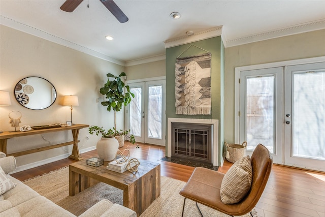 living area featuring crown molding, baseboards, wood finished floors, and french doors