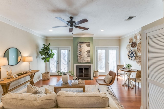 living area with a healthy amount of sunlight, visible vents, wood finished floors, and french doors