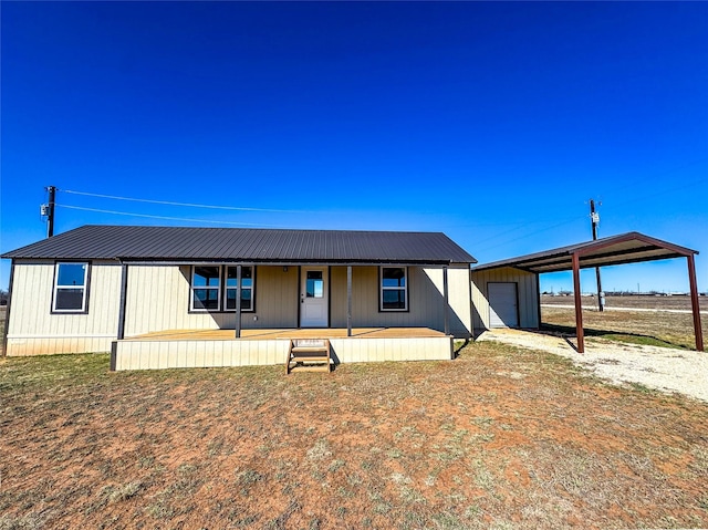 view of front of property featuring an outbuilding, a garage, driveway, metal roof, and a carport