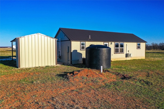 rear view of property featuring metal roof, a yard, and an outdoor structure