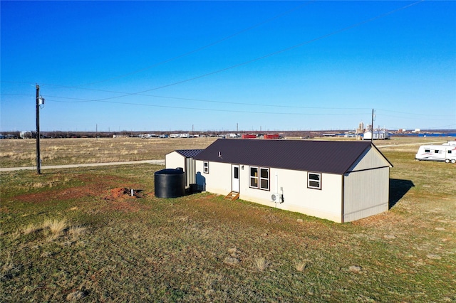 rear view of house featuring metal roof and a yard