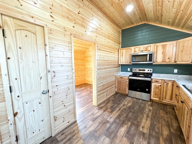 kitchen featuring vaulted ceiling, wooden walls, appliances with stainless steel finishes, and light brown cabinetry