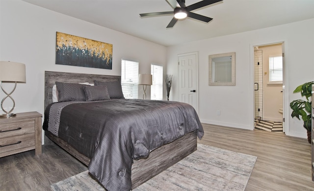bedroom featuring ensuite bath, baseboards, a ceiling fan, and wood finished floors