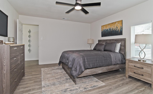 bedroom featuring ceiling fan, wood finished floors, and visible vents