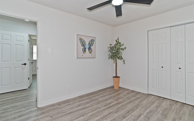 unfurnished bedroom with light wood-style flooring, baseboards, a closet, and ceiling fan