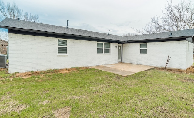 back of house featuring roof with shingles, central air condition unit, brick siding, a patio area, and a lawn