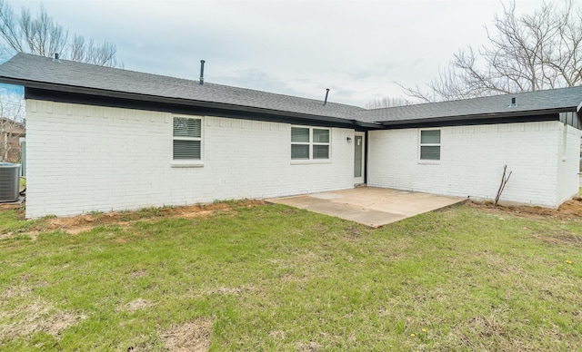 back of property with a yard, a patio, brick siding, and central AC