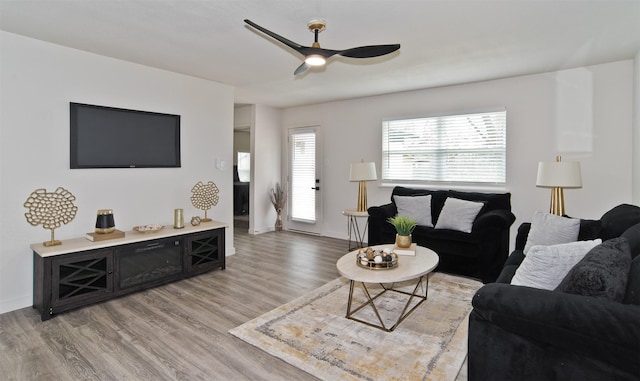 living room featuring ceiling fan, baseboards, and light wood finished floors
