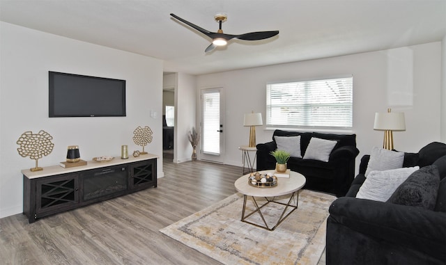 living room featuring light wood-type flooring, a ceiling fan, and baseboards