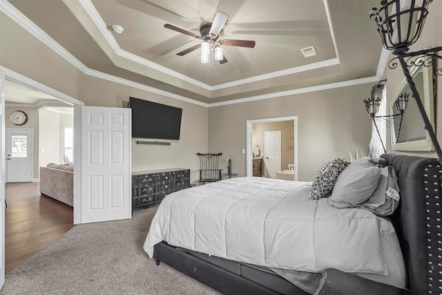 bedroom with ornamental molding, a tray ceiling, visible vents, and ensuite bathroom