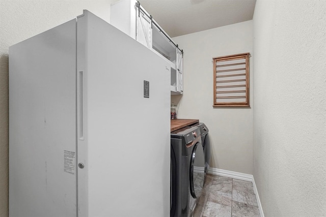 laundry room featuring washer and clothes dryer, cabinet space, and baseboards