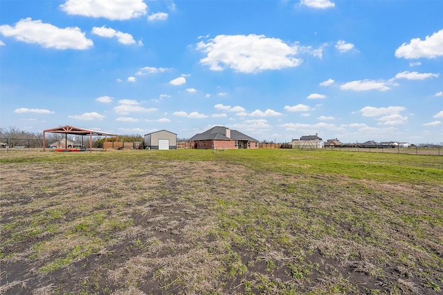 view of yard featuring a rural view, fence, and an outdoor structure