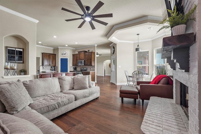 living room featuring ceiling fan, recessed lighting, dark wood-style flooring, baseboards, and a brick fireplace