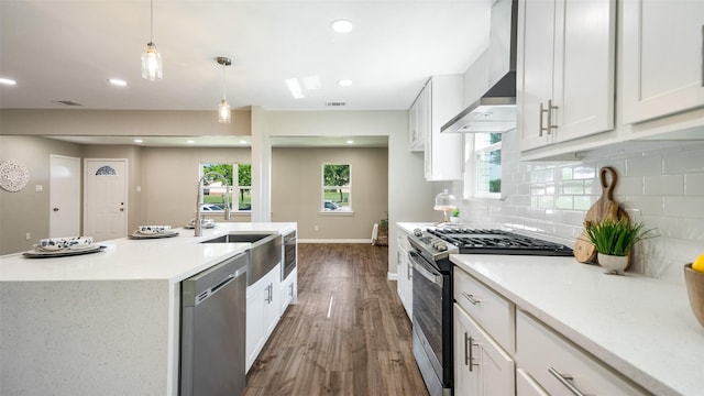 kitchen featuring stainless steel appliances, wall chimney range hood, and white cabinetry