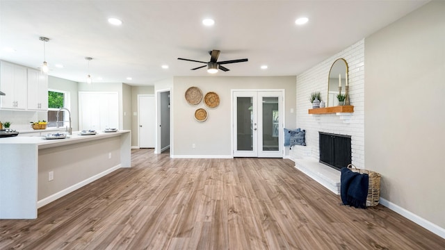 unfurnished living room with baseboards, french doors, light wood-style floors, a fireplace, and recessed lighting