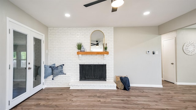 living area with a fireplace, a ceiling fan, and wood finished floors