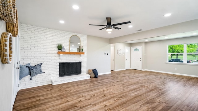 living room featuring a brick fireplace, wood finished floors, and visible vents