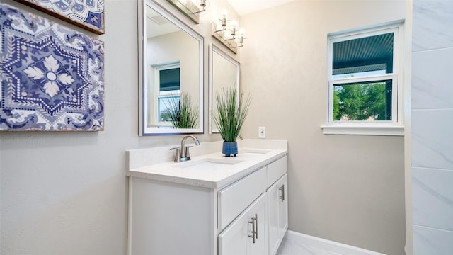 bathroom with marble finish floor, a sink, baseboards, and double vanity